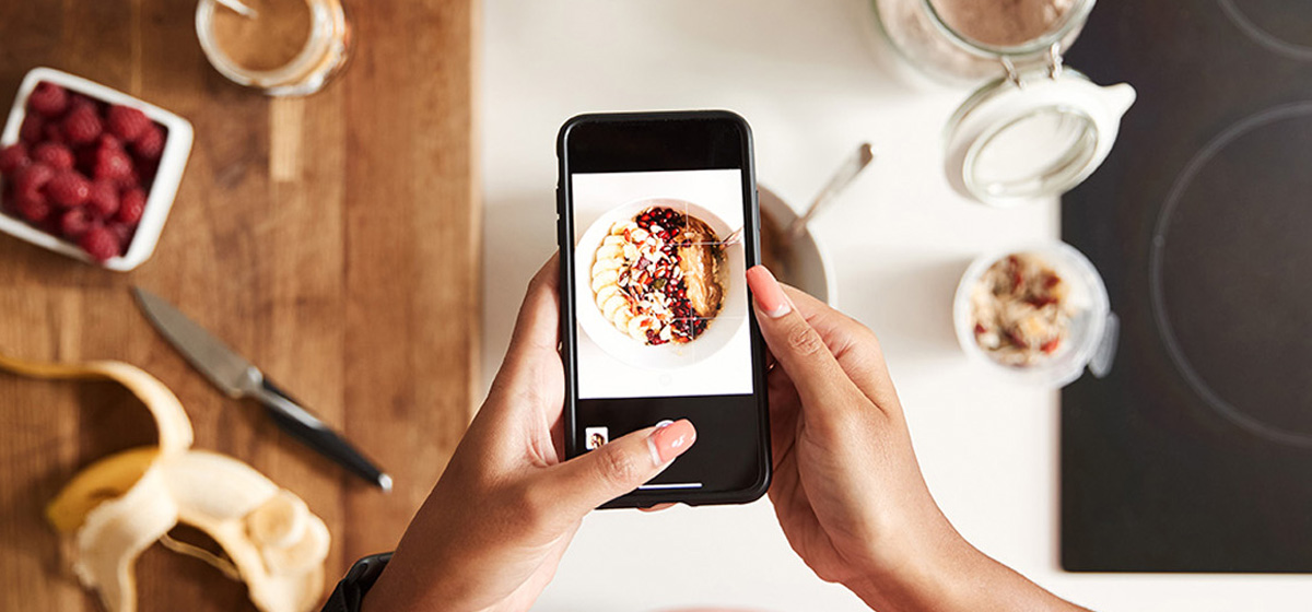 a person holding a phone taking a picture of a meal