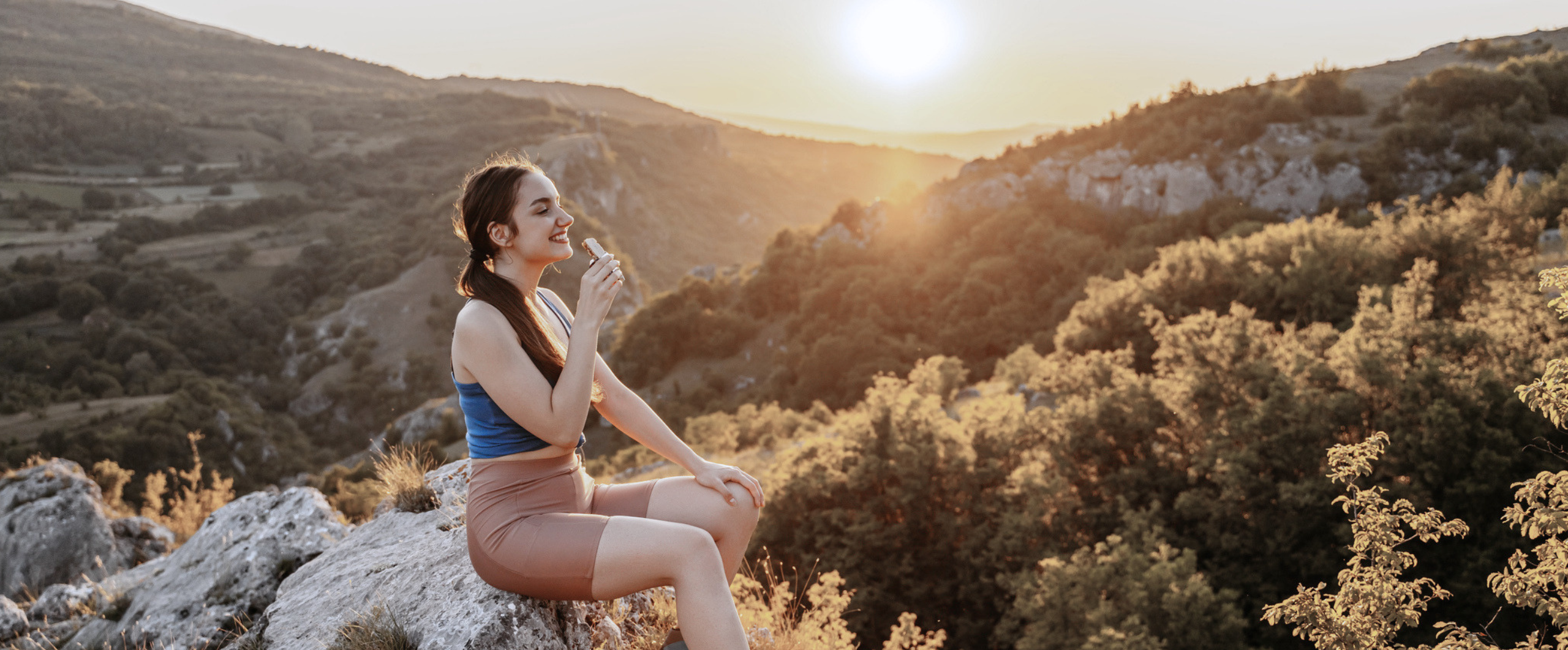 woman eating protein bar on a hike