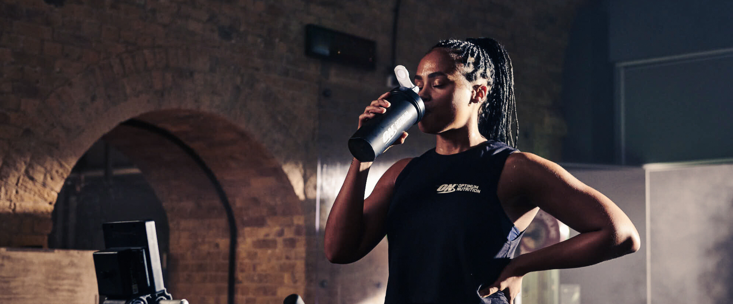 woman in gym drinking optimum nutrition