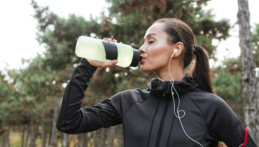 woman drinking from a bottle while exercising 