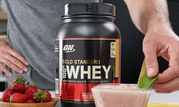 an optimum nutrition gold standard whey tub with a man in the background