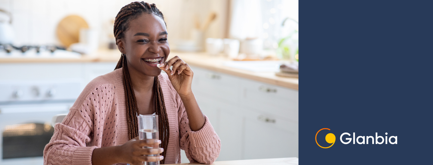 woman smiling while eating and holding a glass of water
