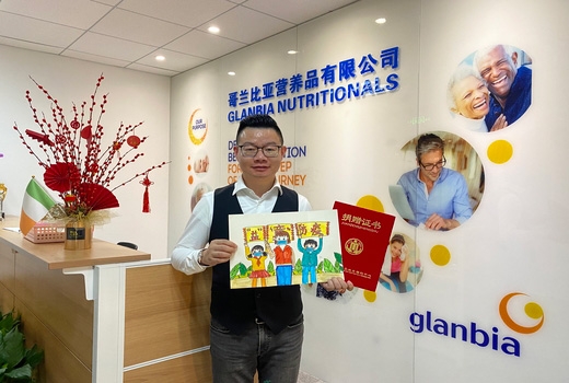 glanbia employee holding a picture and booklet for the suzhou children hospital