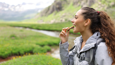 woman eating a bar outside