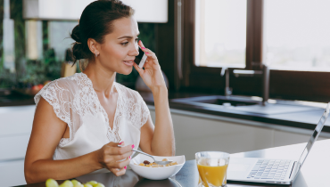 woman eating breakfast while on the phone