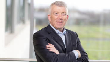 Hugh Mcguire with his arms crossed in a suit