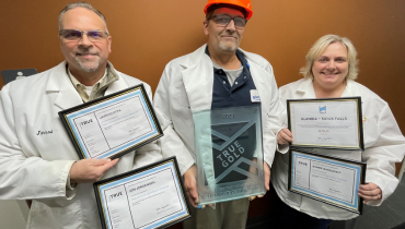 three people in lab coats holding certificates and awards