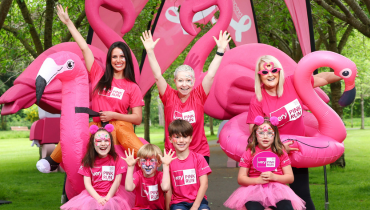 women and children in pink breast cancer awareness t-shirts holding inflatable flamingos