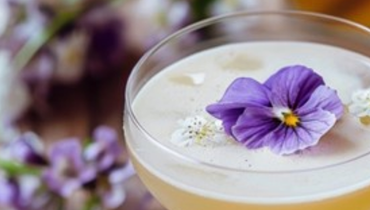 cocktail in glass with flower on top of it
