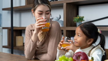 woman and girl sitting at a table drinking juice