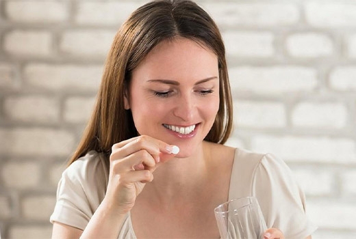 a woman taking a vitamin tablet