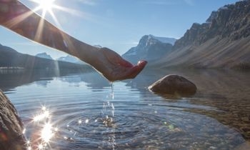 hand lifting water from a beautiful lake on a bright day