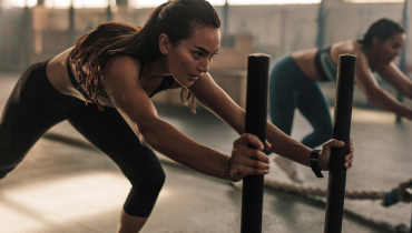 two women pushing sleds in the gym