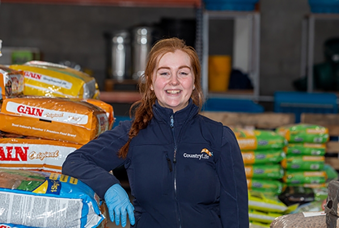 glanbia employee smiling surrounded by bags of animal food