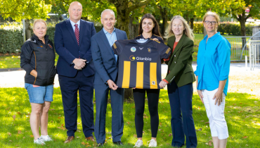 Glanbia employees handing jersey to Kilkenny camogie player