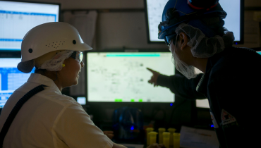 two people in protective gear looking at a computer screen