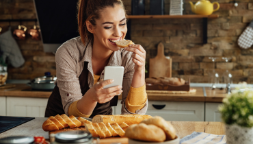girl eating bread and looking at phone