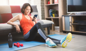 girl sitting on the ground wearing gym gear on her phone