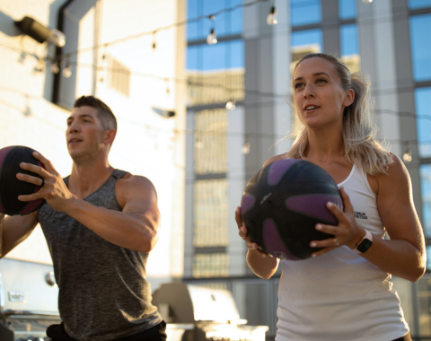 man and woman in active wear holding medicine balls