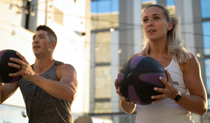man and woman holding medicine balls, fitness