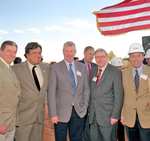 Group of men in suits standing in front of an American flag
