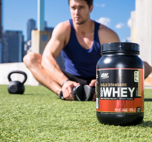 man sitting down with kettlebell beside him and a tub of whey protein in front of him