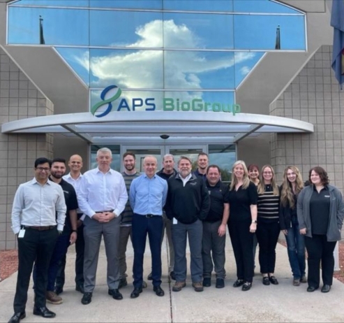 group of people standing outside an APS Biogroup building