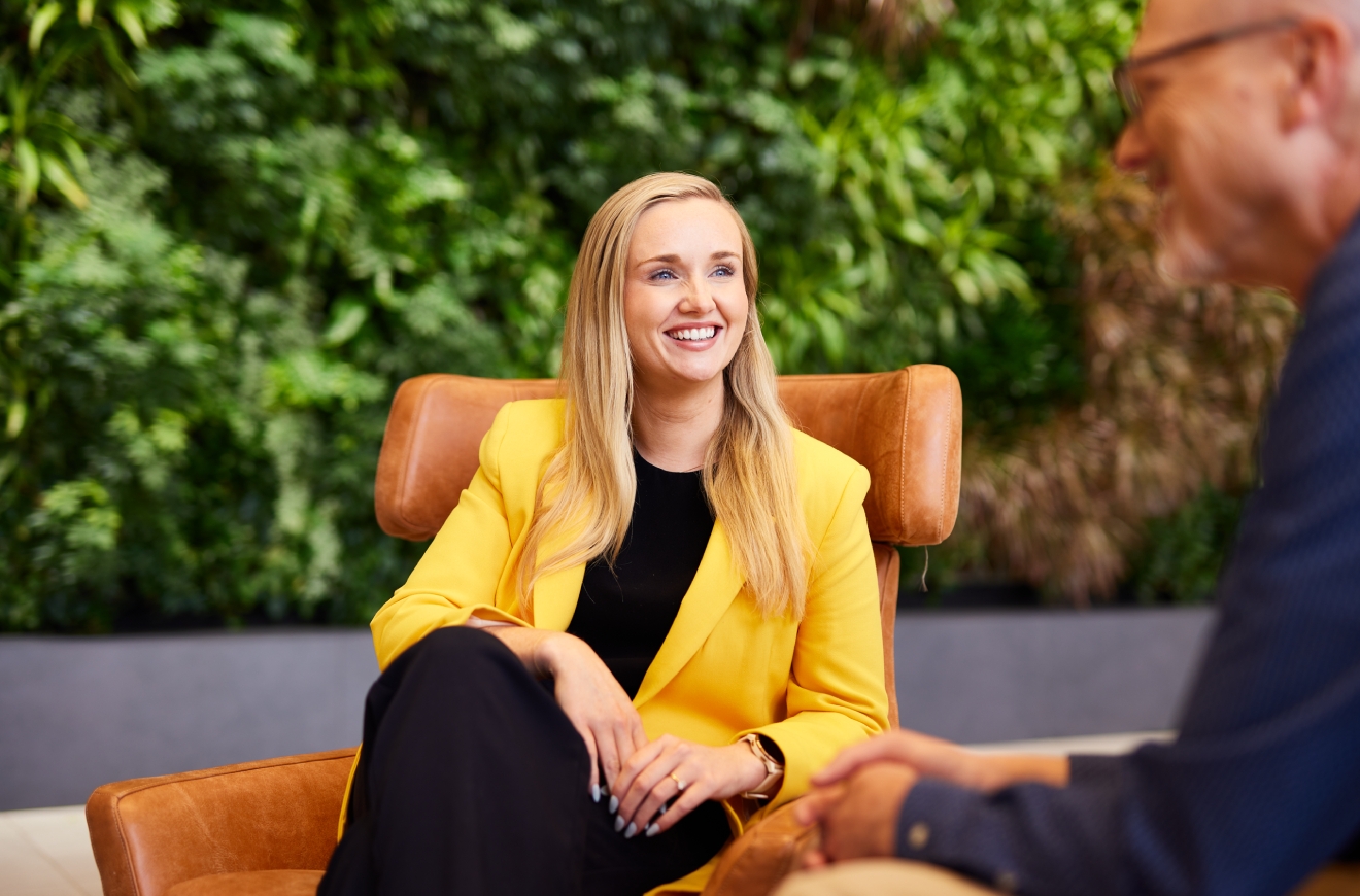 woman wearing yellow jacket sitting on a chair and talking