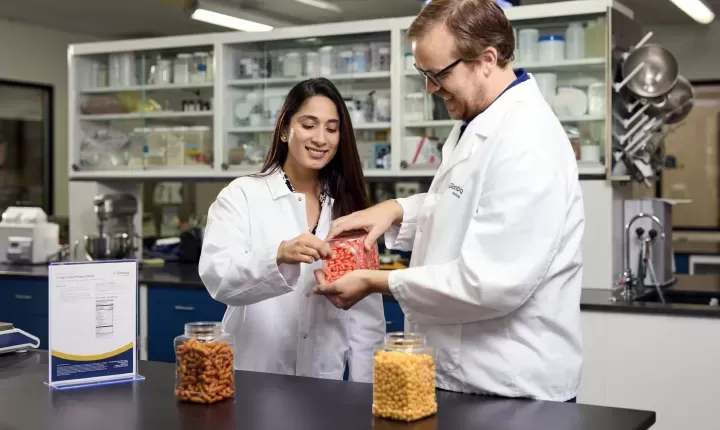 two people pouring ingredients from a tub in a lab
