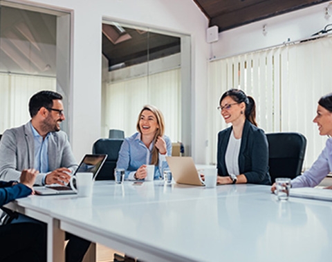 a group of people sitting around a table laughing and discussing
