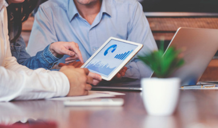 a group of people holding a tablet and pointing to the screen