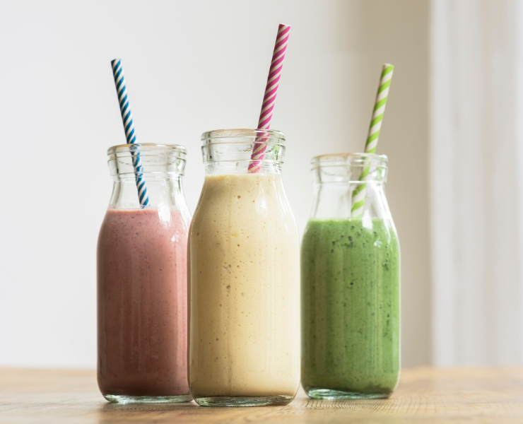 3 healthy smoothies in a glass bottles with straws