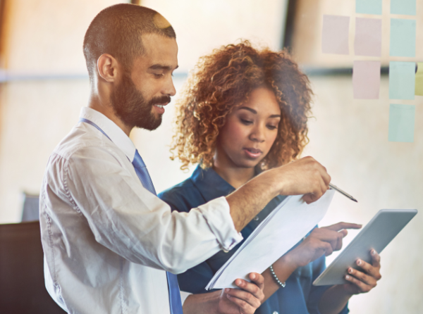 man and woman discussing while holding notepads