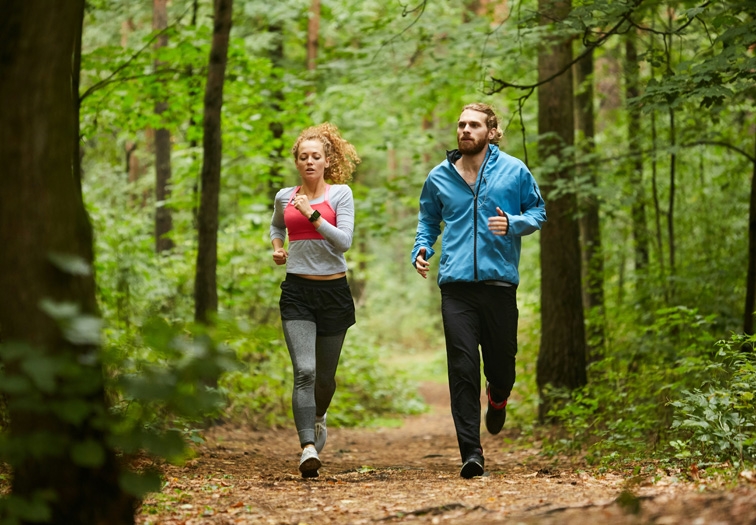 man and woman running in a forest 