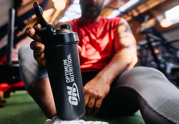 man sitting down holding an optimum nutrition bottle