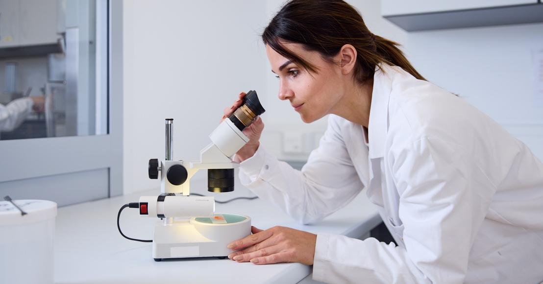 woman looking into microscope