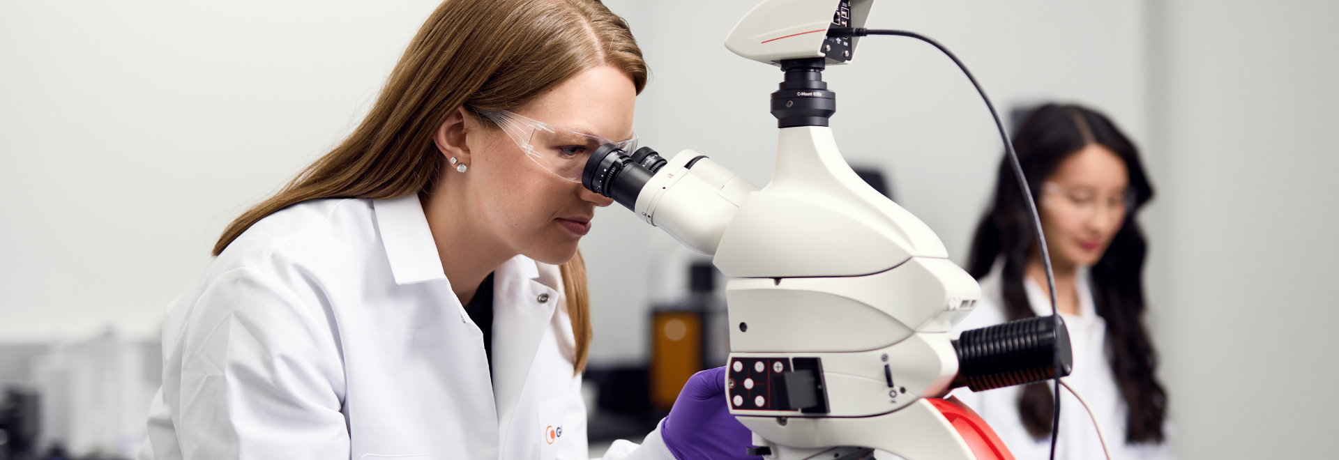 two women, microscope, lab