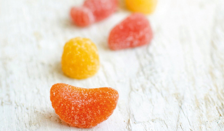 Colorful sugar-coated gummy candies scattered on a light wooden surface.