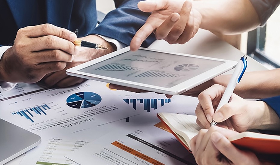 a group of people looking at a tablet with graphs