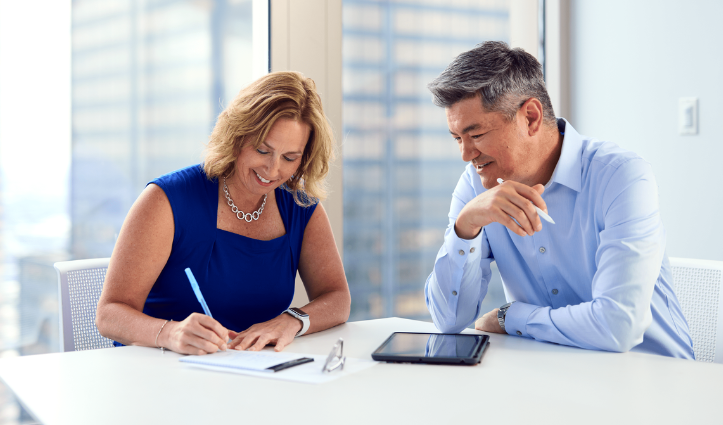 two people sat at a table discussing and taking notes