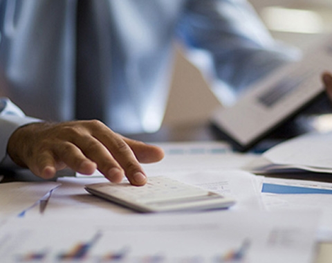 persons hand with calculator and a book