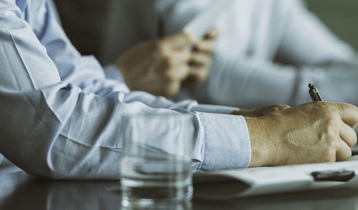 a glass water on table while person is writing