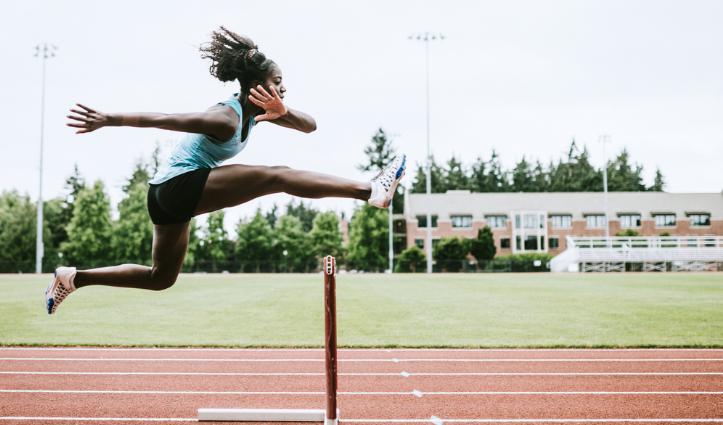 girl jumping over hurdle