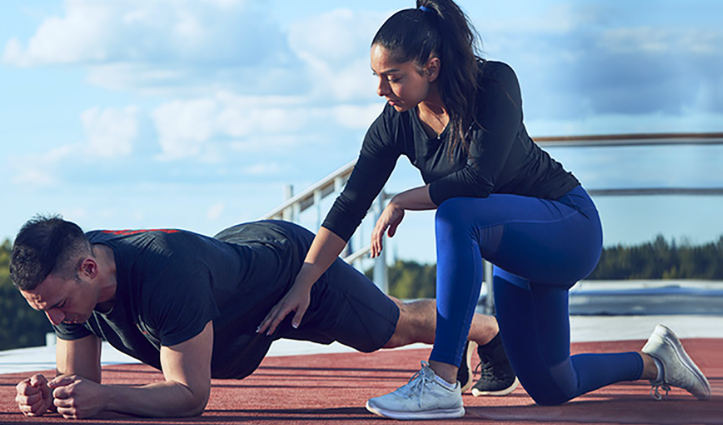 man holding a plank and a woman kneeling down beside him