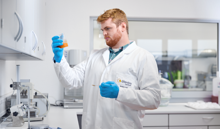 Man working in a lab holding orange liquid in a cup