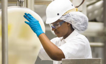 woman working in a lab pouring from a large tub