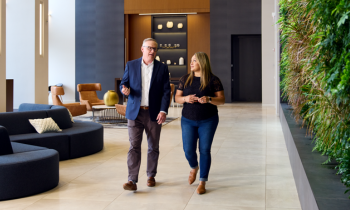 man and woman walking down a hallway discussing