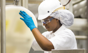 woman working in a lab pouring from a large tub