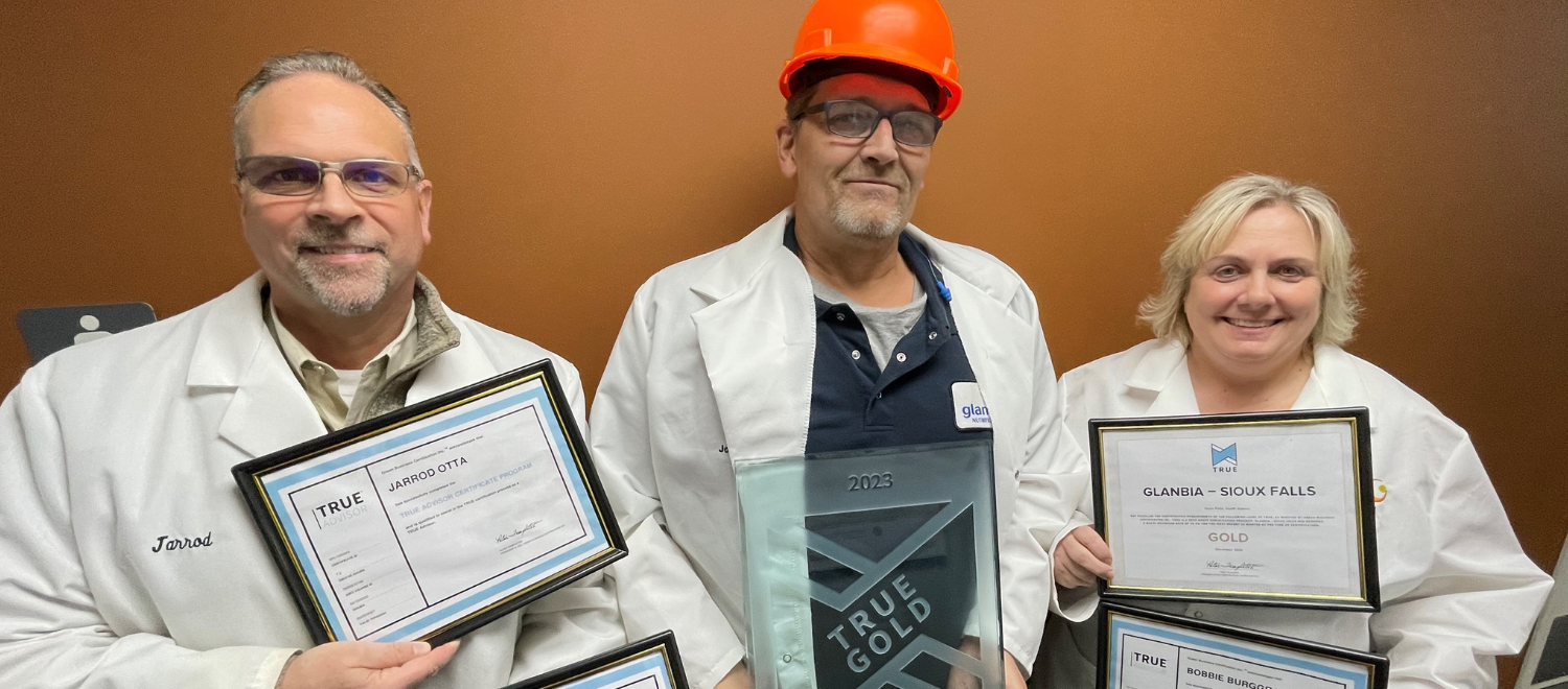 two men and a woman standing with certificates
