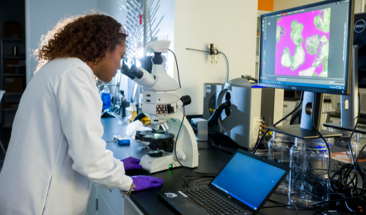 woman looking into a microscope in a lab